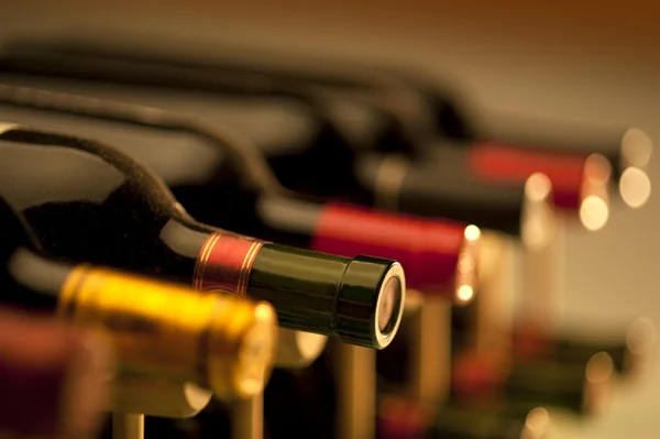 SIx bottles of wine laying on sides in a wine rack.